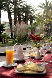 a table with a plate of food and glasses of orange juice at Art suites in El Jadida