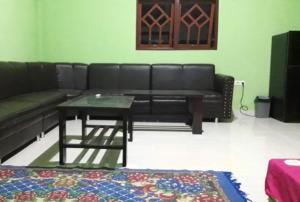 uma sala de estar com um sofá preto e uma mesa em Penginapan asidik em Bira