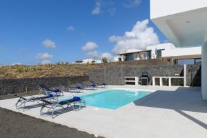 une piscine avec des chaises et une maison dans l'établissement Villa Ainara, à Vegas de Tegoyo