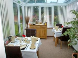 a room with tables and chairs in a conservatory at Eden's Rest Bed and Breakfast in St Austell