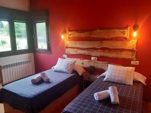 Duas camas num quarto com paredes vermelhas e janelas em EL ABEDUL em Beloncio