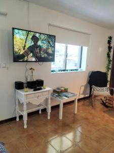 sala de estar con mesa blanca y TV en la pared en Pé na Aldeia, en Outeiro