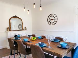 a dining room table with chairs and a clock on the wall at Week2Week 4 BEDROOM BEACH HOME Free Netflix & Wifi in South Shields