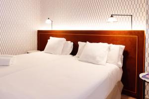 1 cama grande con sábanas y almohadas blancas en THE APARTMENT by assethoteles, en Torrejón de Ardoz
