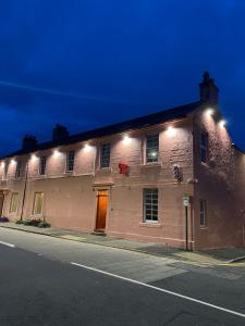 a large brick building with lights on the side of it at Queensberry arms hotel in Kirkconnel