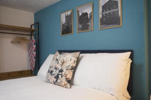 een slaapkamer met blauwe muren en een bed met een kussen bij K Suites - Wellington Street 3 in Gloucester