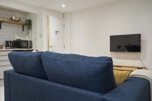 een blauwe bank in een woonkamer met een tv bij K Suites - Wellington Street 3 in Gloucester