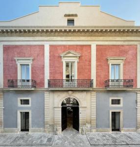 un grand bâtiment rouge et blanc avec une porte dans l'établissement Palazzo Tafuri, à Nardò