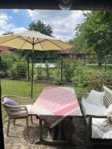 a table with an umbrella and two chairs and a couch at Moderne trifft auf Fachwerk in Wedemark