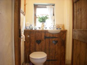a bathroom with a toilet and a sink and a window at The Nest - Thatched seaside country cottage for two in Stokeinteignhead
