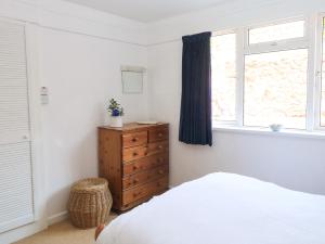 ein Schlafzimmer mit einem Bett, einer Kommode und einem Fenster in der Unterkunft Flat 18 in Paignton