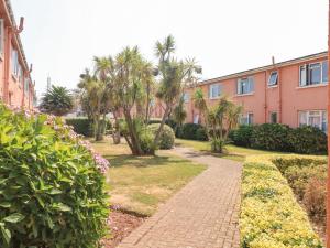 a brick walkway in front of a building with palm trees at Flat 18 in Paignton