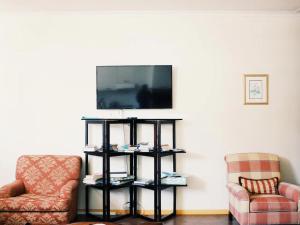 uma sala de estar com duas cadeiras e uma televisão em Scalabrini Accommodation em Cidade do Cabo