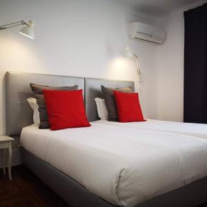 a large bed with two red pillows on it at The Bulldog Inn - Duna Parque Group in Vila Nova de Milfontes