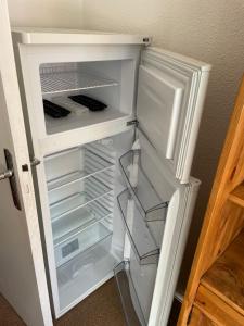 einem leeren Kühlschrank mit offener Tür in einem Zimmer in der Unterkunft APPARTEMENT VUE MONTAGNE AU PIED DES PISTES in Allos