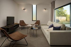 ein Wohnzimmer mit einem Sofa, Stühlen und einem TV in der Unterkunft Villa Monte D'Or in Krnica