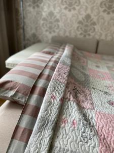 a bed with a pink and white quilt on it at Venta apartament in Mažeikiai
