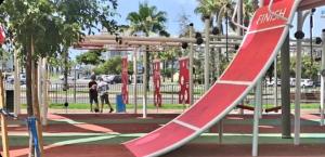 einen Spielplatz mit einer roten Rutsche in einem Park in der Unterkunft 1351 דירת סטודיו עם מרפסת מול הים in Bat Yam