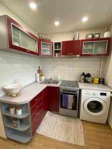 a kitchen with red cabinets and a washing machine at Venta apartament in Mažeikiai