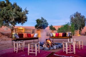 a fire in the middle of a desert with beds and chairs at Ali & Sara's Desert Palace in Merzouga