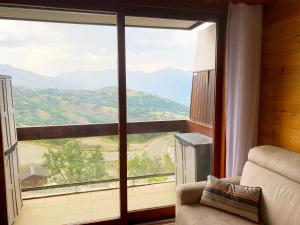 Una habitación con una gran ventana con vistas a las montañas. en Appartement avec balcon au pied des pistes de ski, en Villarembert