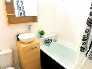 y baño pequeño con lavabo y bañera. en Appartement avec balcon au pied des pistes de ski, en Villarembert