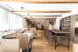 a dining room with tables and white chairs at Relais Lucomagno in Olivone