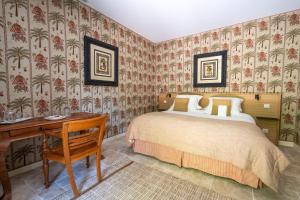 a bedroom with a bed and a desk and wallpaper at La Chapelle Saint Martin in Nieul