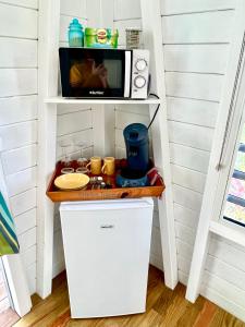 a small kitchen with a microwave on a shelf at Le Surf Lodge, chambre avec vue mer dans un écrin de verdure in Deshaies