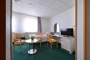 Habitación con sillas, mesa y TV. en Hotel Im Kräutergarten, en Cursdorf