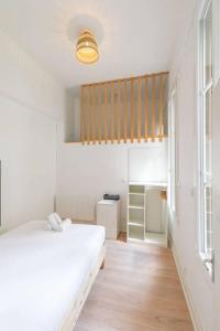 een slaapkamer met een wit bed en een houten vloer bij Le Graine de Moutarde in Dijon