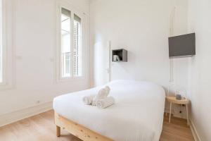 een witte kamer met een bed met handdoeken erop bij Le Graine de Moutarde in Dijon