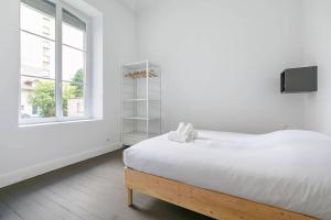 een witte slaapkamer met een groot bed en een raam bij Le Graine de Moutarde in Dijon