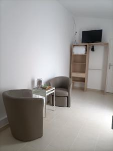 a living room with a table and chairs and a television at La Grimodière Chambre en rez de chaussée in Ranville