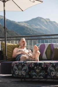 Ein Mann auf einer Couch mit erhobenen Füßen in der Unterkunft Anthony's Life&Style Hotel in Sankt Anton am Arlberg
