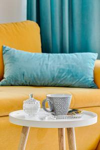 a coffee table with two cups and a couch at ARI BLUE Apart în complexul Ared Kaufland in Arad