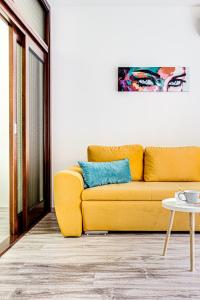 um sofá amarelo numa sala de estar com uma mesa em ARI BLUE Apart în complexul Ared Kaufland em Arad