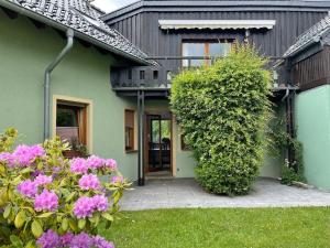 a green house with pink flowers in the yard at Behagliches Haus mit Kamin in Monschau