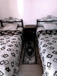 um quarto com 2 camas individuais e um tapete em Roshel em Bosteri