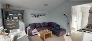 sala de estar con sofá púrpura y mesa en Rekerlanden 253 en Schoorldam