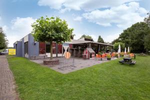 a park with a building with a tree and chairs at Rekerlanden 253 in Schoorldam