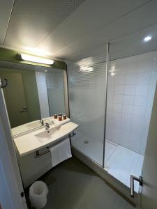 a bathroom with a shower and a sink and a mirror at Ibis Budget Marseille Est Porte d'Aubagne in Marseille +94 photos