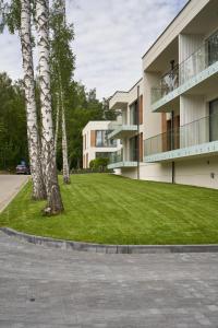 un bâtiment avec une pelouse verte à côté d'un arbre dans l'établissement Apartament Olimpijska 116, à Olsztyn