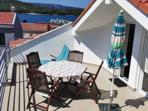 balcón con mesa, sillas y sombrilla en Apartments Mara Cres, en Cres