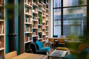 a library with bookshelves and a table and chairs at Aris Grand Place Hotel in Brussels
