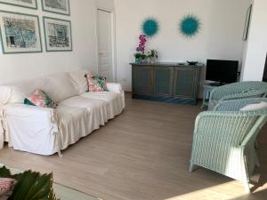 uma sala de estar com um sofá branco e duas cadeiras em Appartamenti a 50 m dal mare da Cecimia's Holiday em Olbia