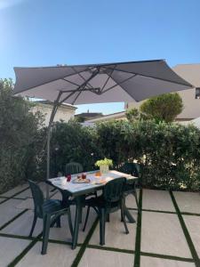 uma mesa e cadeiras sob um guarda-sol num pátio em Appartamenti a 50 m dal mare da Cecimia's Holiday em Olbia