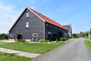 a large black barn with a red roof at Appartement 5 in Vrouwenpolder