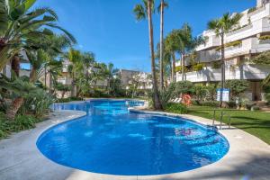 una gran piscina azul con palmeras frente a un edificio en FA- Luxury 2 bedroom apt Fuente Aloha en Marbella