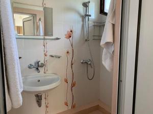 a bathroom with a sink and a shower with flowers on the wall at Петрови in Chernomorets